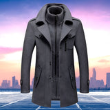 Men's charcoal grey wool blend tailored winter overcoat against a clear blue sky background.