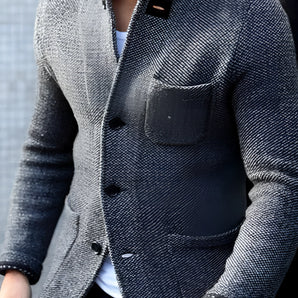 Men's charcoal tweed blazer in a slim fit design, featuring a wool herringbone pattern, shown in gray color, size 4XL. The model pairs it with a white dress shirt and is smiling.