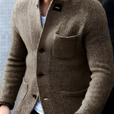 Men's charcoal tweed blazer in a slim fit, featuring a herringbone pattern. The model is wearing a dress shirt and a watch, showcasing the blazer's versatility for formal wear. The blazer color is primarily grey with hints of black, complementing the model's beard.