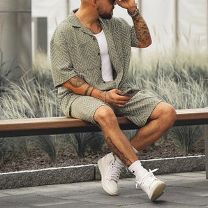 Men's geometric print short set summer outfit featuring a white shirt with short sleeves and matching shorts, worn by a model accessorized with a hat, stylish and perfect for a fashion-forward summer look.