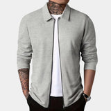 Men's gray slim fit blazer designed for casual wear, featuring a lightweight and urban style. The image shows the blazer being worn over a white dress shirt. The blazer has a sleek collar and long sleeves.