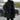 Men's black hooded insulated parka, long puffer winter coat with grey accents, worn by a person standing.