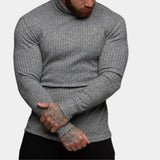 Men's grey knit turtleneck sweater in a fitted muscle fit style, showcasing long sleeves and a high neckline, modeled by a bearded man wearing size XL.