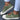 Men's grey slip-on casual sneakers with hook and loop closure, featuring a lightweight design. The shoes are displayed against a white background, showcasing their sleek and fashionable look.