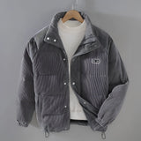 Men's grey quilted puffer jacket with corduroy patchwork detailing, featuring a collared neck and long sleeves, designed for winter wear.