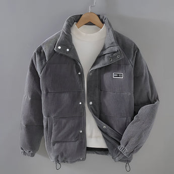 Men's grey quilted puffer jacket with corduroy patchwork detailing, featuring a collared neck and long sleeves, designed for winter wear.