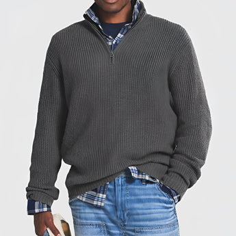 Men's grey ribbed half-zip sweater shown worn over a white dress shirt, paired with jeans. The sweater is a part of fall and winter knitwear collection, designed for comfort and style. Model with a beard wears the sweater, which features a ribbed texture and extended sleeves, suitable for casual or semi-formal occasions.