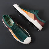 Men's grey slip-on sneakers featuring red accents, designed for style and comfort, with a sleek athletic look and subtle branding elements.