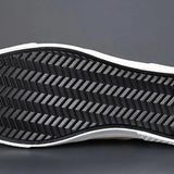 Men's grey slip-on sneakers with red accents, featuring synthetic rubber soles, designed for style and comfort in walking and outdoor activities.