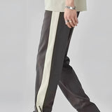 Men's grey tapered joggers featuring two-tone stripes along the sides, with practical pockets and comfortable ankle cuffs, styled in a contemporary fashion.