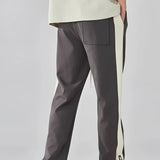 Men's grey tapered joggers featuring two-tone stripes, side pockets, and fitted ankle cuffs.