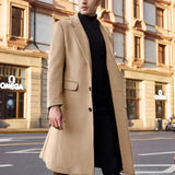 Men's khaki wool winter overcoat in size 3XL, displayed hanging near a window with its stylish urban fashion cut visible. The coat features a high neck and shoulder design, similar to a trench coat style, with a focus on its beige textile.