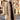 Men's khaki wool winter overcoat in size 3XL, displayed hanging near a window with its stylish urban fashion cut visible. The coat features a high neck and shoulder design, similar to a trench coat style, with a focus on its beige textile.