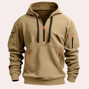 Men's khaki tactical hoodie with zipper pockets, reinforced elbows, and long sleeves, displayed in size XL. The hoodie features a zip-up front and a high collar for added protection.