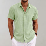 Men's linen henley short sleeve shirt in yellow-green, size 3XL, featuring a breathable and casual design suitable for summer. The shirt has a collar and a buttoned neckline, with sleeves reaching just above the elbow. The model is wearing a watch on one arm.