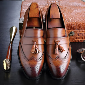 Men's luxury brown leather brogue tassel loafers in a slip-on design, size 48, featuring intricate stitching and perforations, displayed against a wooden background.