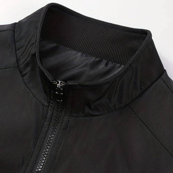 Men's minimalist black bomber jacket featuring a sleek design with a front zipper, ribbed cuffs, and collar, paired with blue jeans.