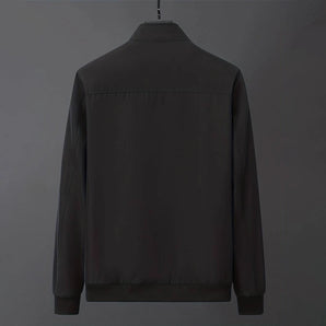 Men's minimalist black bomber jacket on a clothes hanger, featuring a sleek design with a collar, button details, and long sleeves.