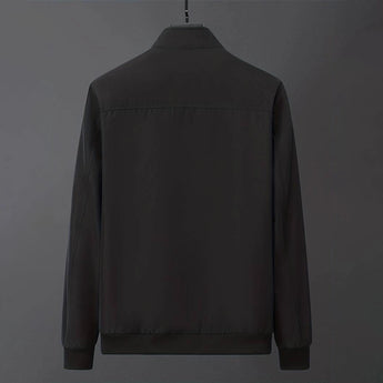Men's minimalist black bomber jacket on a clothes hanger, featuring a sleek design with a collar, button details, and long sleeves.