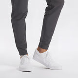 Men's light grey moisture-wicking quick-dry athletic t-shirt worn by a person with sneakers visible.