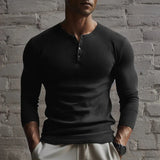 Men's muscle-fit grey Henley shirt modeled by a man with a beard, showcasing the slim-fit thermal design and long sleeves, in a casual setting.