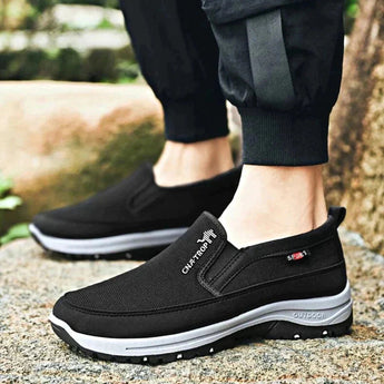 Men's navy slip-on walking shoes showcased outdoors, featuring a lightweight and waterproof design with anti-slip soles, paired with denim jeans on grass.