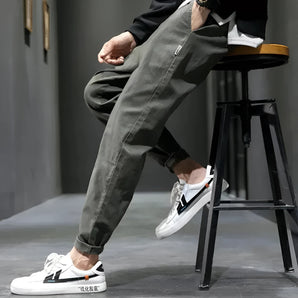 Men's olive green cargo pants in a relaxed fit featuring a zipper pocket, designed in an urban style, shown from waist to ankle.