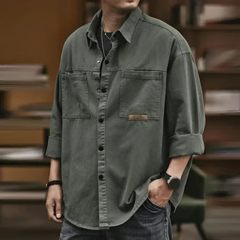 Men’s oversized olive green utility shirt made of cotton, featuring long sleeves, a collar, and a casual design. The shirt is styled in a military green color, suitable for a relaxed or casual look.