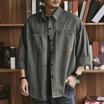 Olive green men's utility shirt in cotton with an oversized, casual long sleeve design, featuring a collar and button-down front.