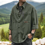 Men's olive green oversized cotton utility shirt with long sleeves, featuring a casual design and a wide collar.