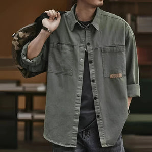 Men's olive green military shirt jacket made of lightweight cotton, featuring a classic collar, long sleeves, and button-up front, worn as an overshirt.