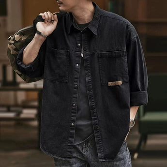 Men's olive green military shirt jacket made of lightweight cotton with a classic collar and long sleeves, shown on a person gesturing with their hands.