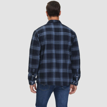 Men's orange plaid flannel shirt with long sleeves featuring a tartan pattern, worn casually.