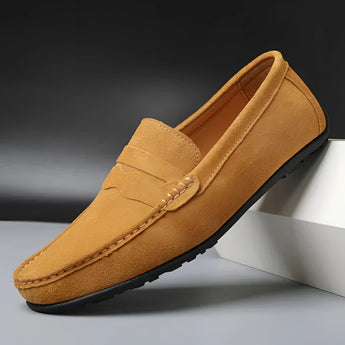 Men's brown suede designer loafers displayed on a model's foot, showcasing luxury casual shoes in a stylish and comfortable design.