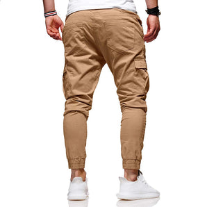 Men's slim fit beige tapered stretch cargo pants with multiple pockets, shown paired with white shoes.
