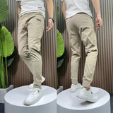 Men's slim fit black cargo pants with a tapered design, shown worn by a model standing, featuring multiple pockets and a versatile style suitable for various occasions. The pants are paired with casual shoes, highlighting their stylish and adaptable nature.