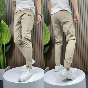 Men's slim fit black cargo pants with a tapered design, shown worn by a model standing, featuring multiple pockets and a versatile style suitable for various occasions. The pants are paired with casual shoes, highlighting their stylish and adaptable nature.