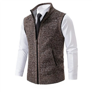 Men's slim fit herringbone tweed vest in brown wool blend, featuring a buttoned front and a tailored design, paired with a formal dress shirt.