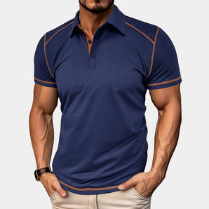 Men's navy blue athletic polo shirt with contrast piping, featuring a slim-fit design. The polo is worn by a person, highlighting the short sleeves, collar, and comfortable fit. The shirt is paired with a watch on the wrist and showcases the marine blue color in size 2XL.