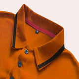 Men's slim-fit navy blue athletic polo shirt with contrast piping, featuring a collared neckline and button-down front, displayed on a model wearing it as part of a stylish outfit.