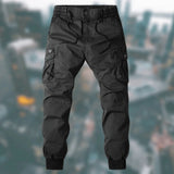 Men's black tactical cargo pants in 3XL size, showcasing durable, water-resistant fabric with multiple pockets, modeled on a person standing next to a tire.