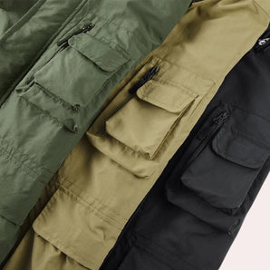 Men's tactical military jacket in a camouflage pattern featuring shades of brown, grey, khaki, and beige; designed with multiple pockets and water-resistant material for durability.