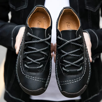 Men's tan leather sneakers with hand-stitched detailing, designed for durability and breathability, displayed on a human leg.