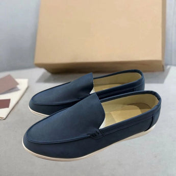 Men's tan suede loafers featuring contrast stitching, displayed as a comfortable slip-on shoe on a wooden surface, highlighting their fashion-forward design.