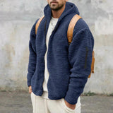 Men's tan teddy bear hoodie zip-up fleece jacket in faux fur, featuring long sleeves and a cozy collar. The model is wearing a marine blue variant in XL size, complementing the outerwear with a grey backdrop and beard, highlighting the garment's soft texture and stylish design.
