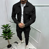 Men's two-tone blue tracksuit in a lightweight fabric, featuring a stylish urban design; shown in Nero color variant, size 3XL, with a contrasting black and grey color scheme, set against a backdrop with a houseplant.