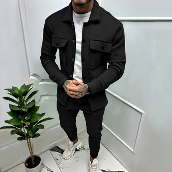 Men's two-tone blue tracksuit in a lightweight fabric, featuring a stylish urban design; shown in Nero color variant, size 3XL, with a contrasting black and grey color scheme, set against a backdrop with a houseplant.
