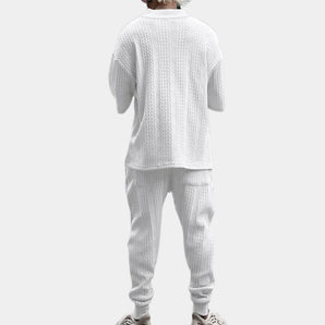 Men's white cable-knit hoodie and pants set featuring a cozy, textured design, perfect for winter wear. The hoodie has a collar and long sleeves, while the pants are tailored for comfort, capturing a casual yet stylish look.