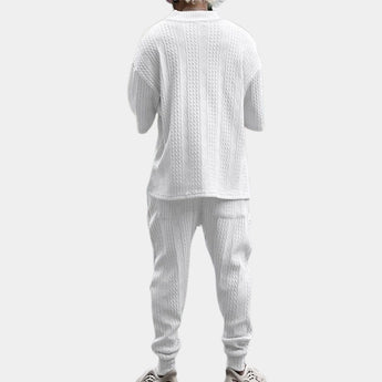 Men's white cable-knit hoodie and pants set featuring a cozy, textured design, perfect for winter wear. The hoodie has a collar and long sleeves, while the pants are tailored for comfort, capturing a casual yet stylish look.