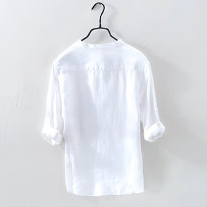 Men's white linen shirt hanging on a clothes hanger, featuring a classic collar and long sleeves, designed for casual wear with a lightweight and breathable fabric.